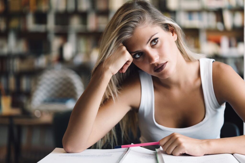 Giovane ragazza stanca che cerca di studiare.